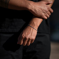 Close-up of a person's hands with a bracelet on a dark background