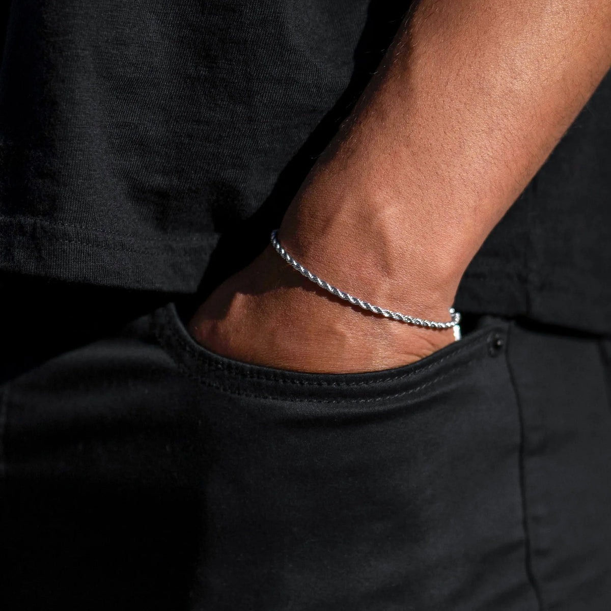 Silver bracelet on a wrist against a black background