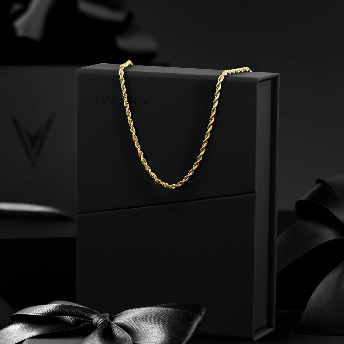 Gold chain on a black box with 'VINCE' branding against a dark background