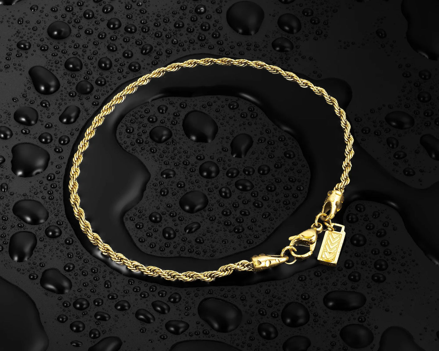 Gold bracelet with a tag on a black textured background