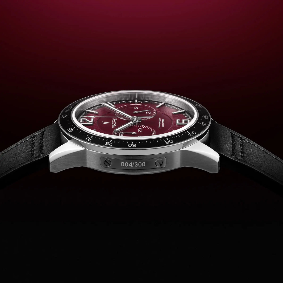 Luxury watch with a red face and black strap on a dark background