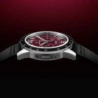 Luxury watch with a red face and black strap on a dark background