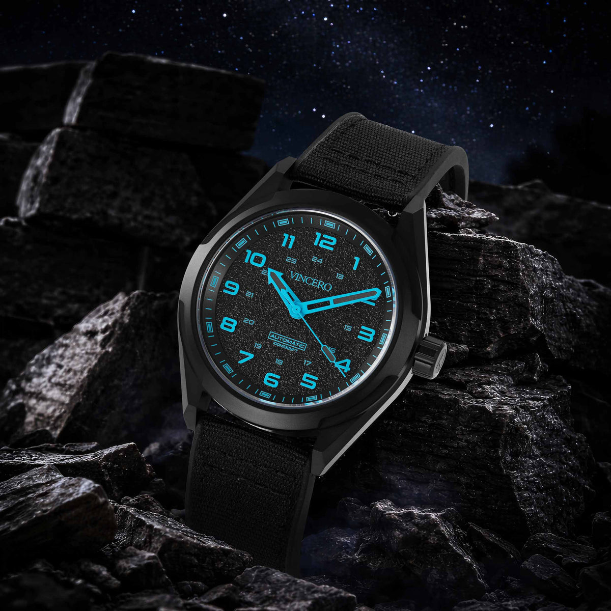 Black wristwatch with blue glowing face on dark rocky surface