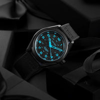 Black wristwatch with glowing blue face on a dark background
