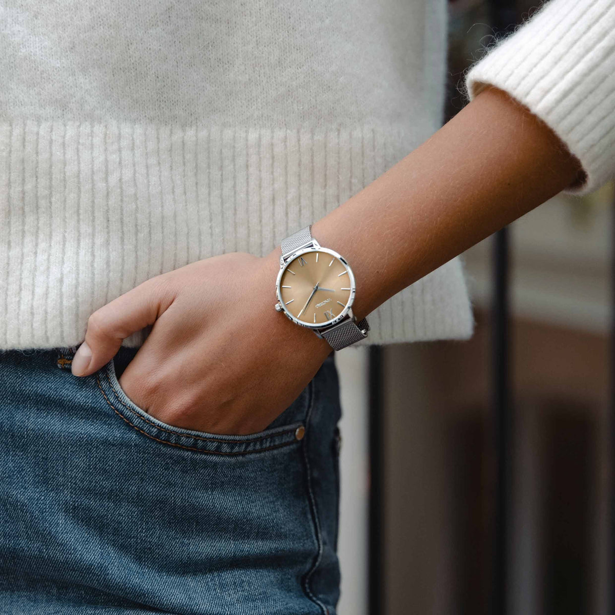 Person wearing a silver watch on a blurred background