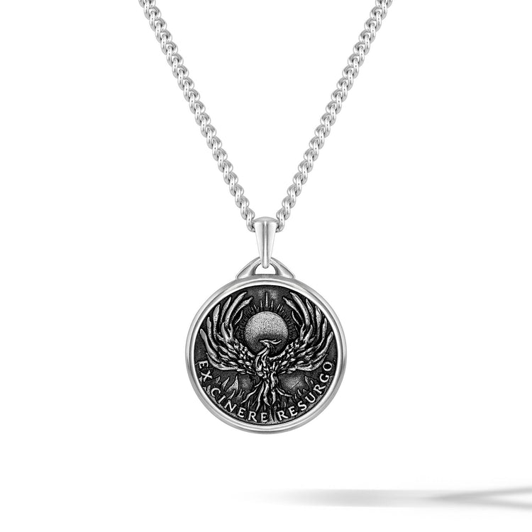 Silver necklace with a round pendant featuring an engraved design on a white background