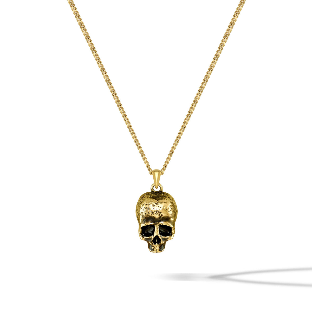 Gold skull pendant necklace on a white background