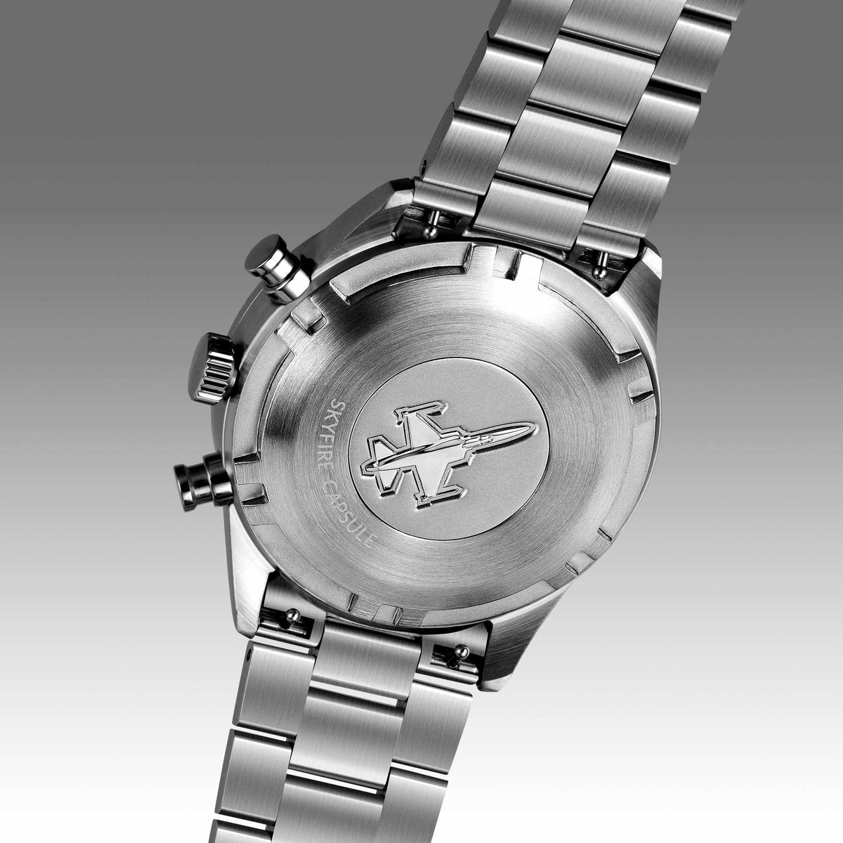 Close-up of a silver watch with a detailed back design on a gray background
