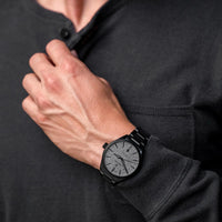 Person wearing a black wooden watch on a dark background
