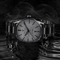 Silver watch with intricate design on a reflective surface and dark background