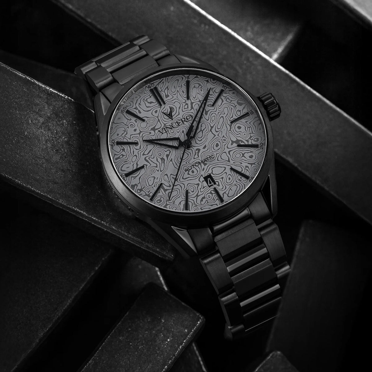 Black wristwatch with intricate design on the dial against a dark background