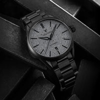 Black wristwatch with intricate design on the dial against a dark background