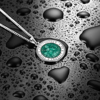 Silver necklace with a green gemstone pendant on a wet surface