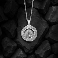 Silver pendant necklace on a dark stone surface