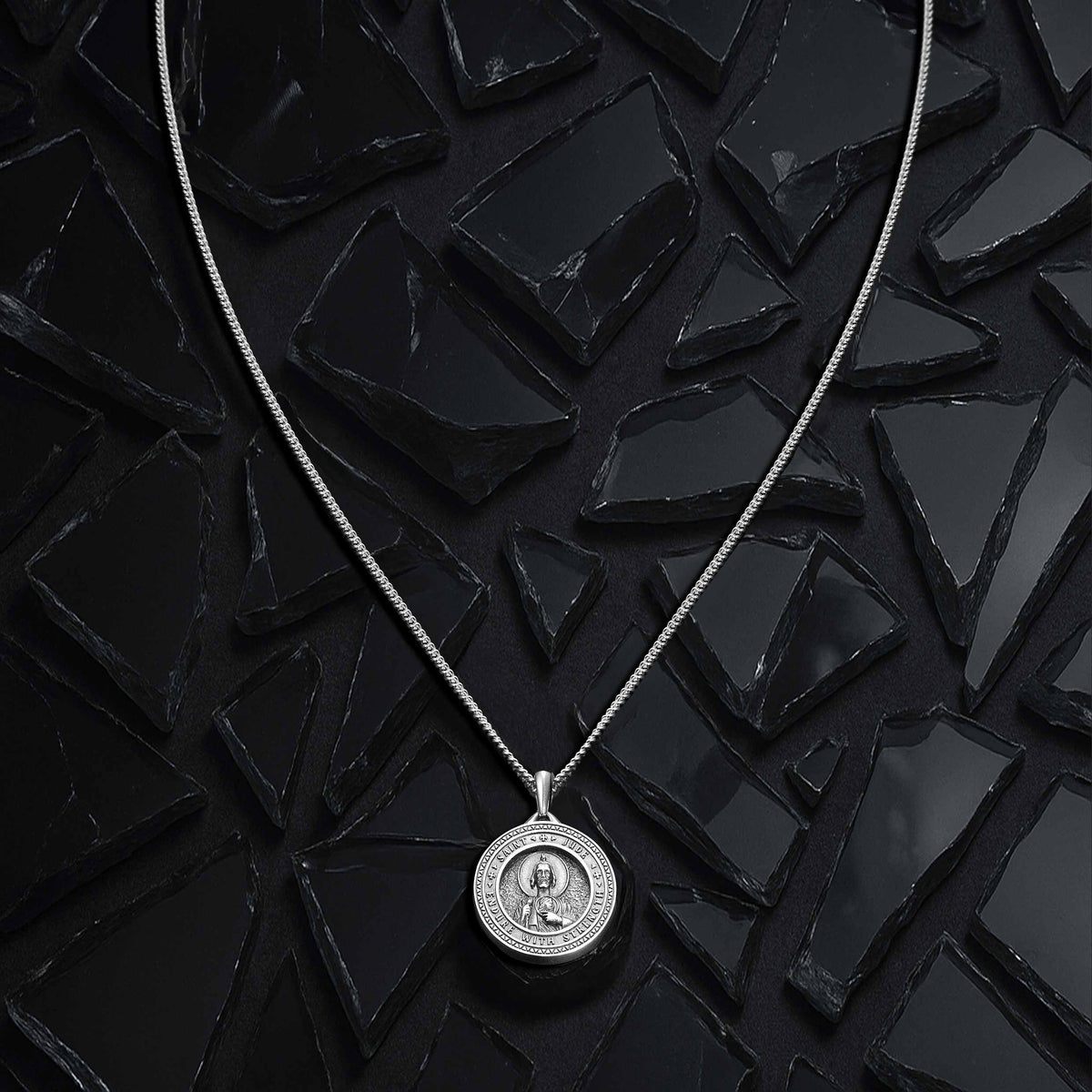 Silver necklace with a round pendant on a black textured background