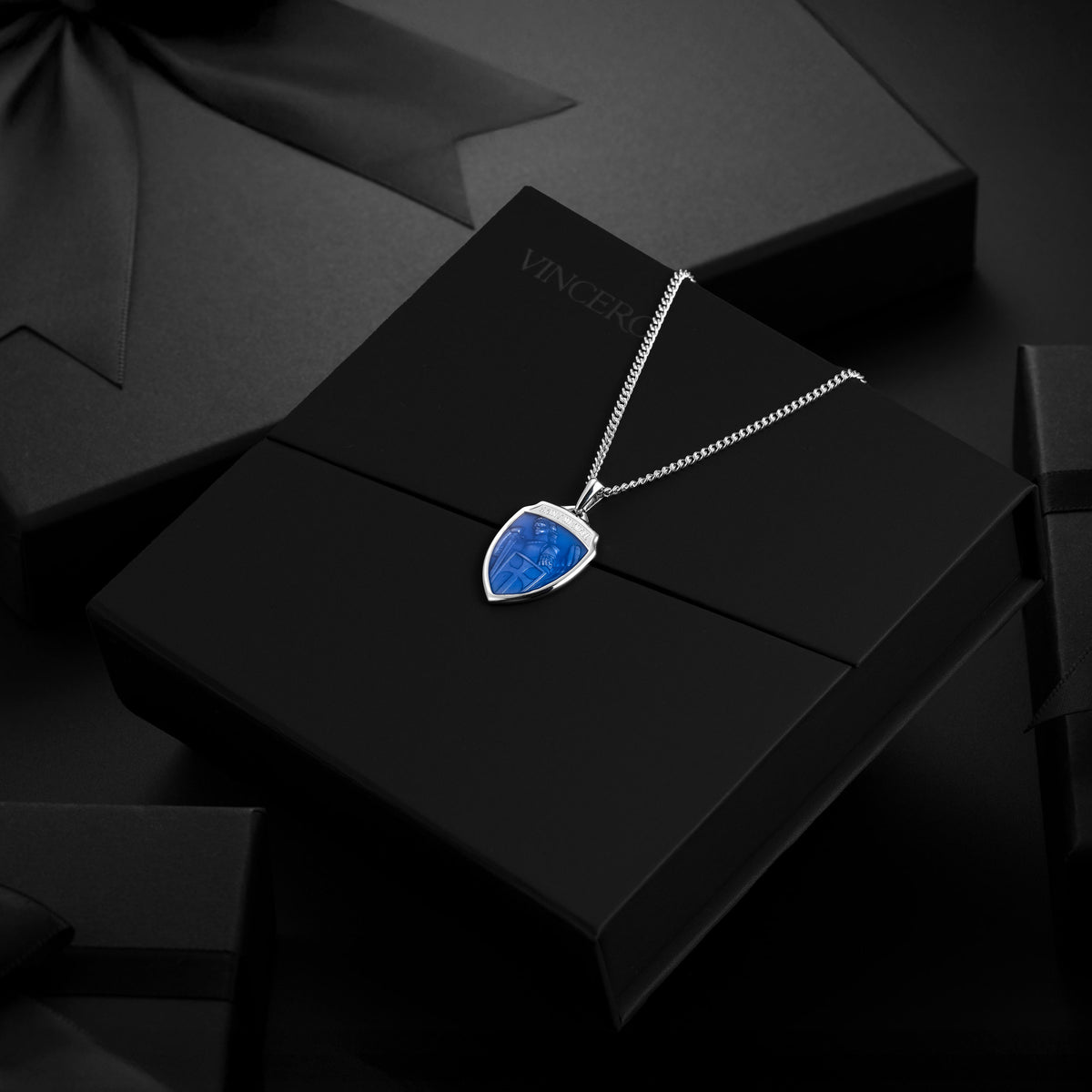Silver necklace with a blue pendant on a black box