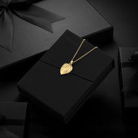 Gold necklace with a leaf pendant on a black box with 'Vincero' branding.