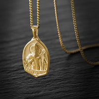 Gold pendant necklace on a dark textured surface