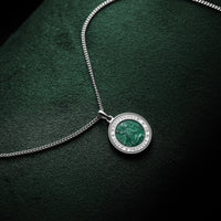 Silver necklace with a round pendant on a dark green background