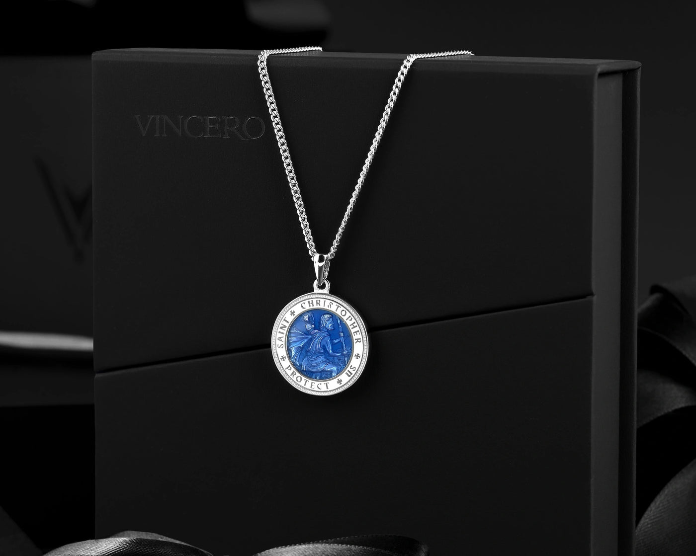 Silver necklace with a blue pendant on a black background
