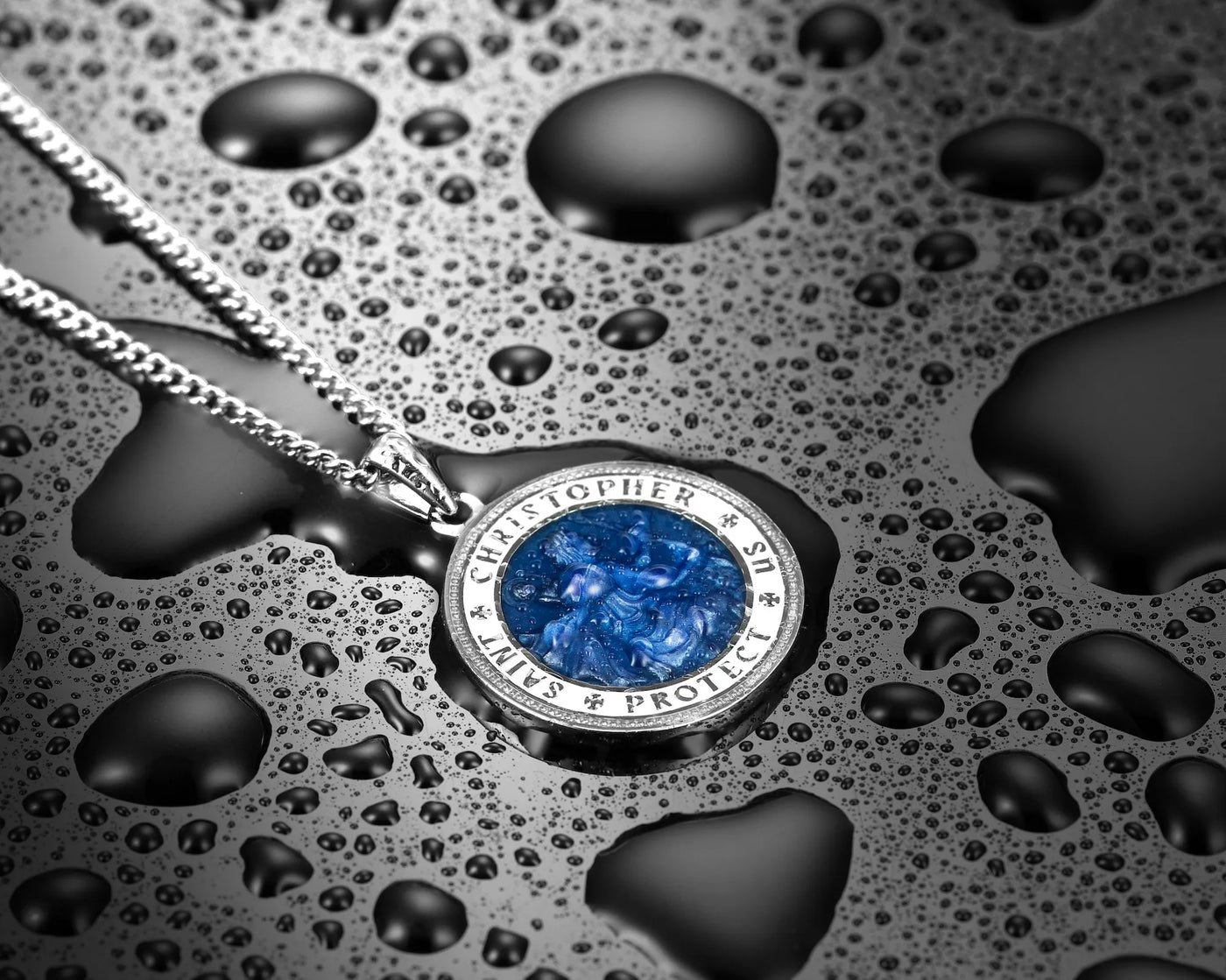 Silver necklace with a blue pendant on a textured black surface