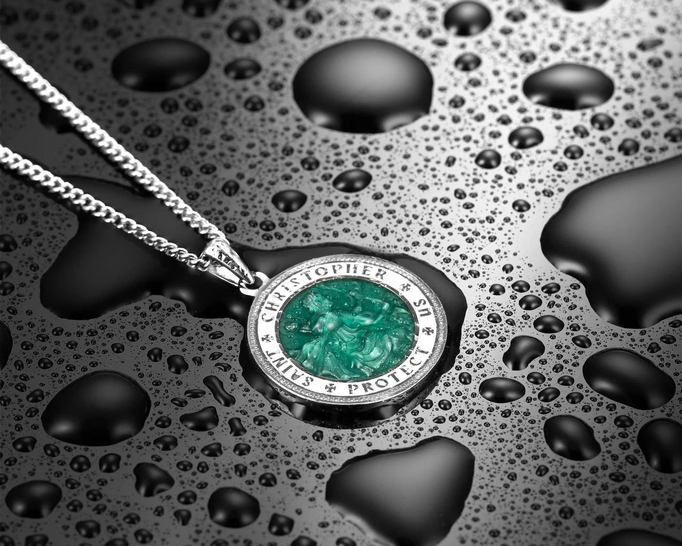 Silver pendant with green gemstone on a textured surface