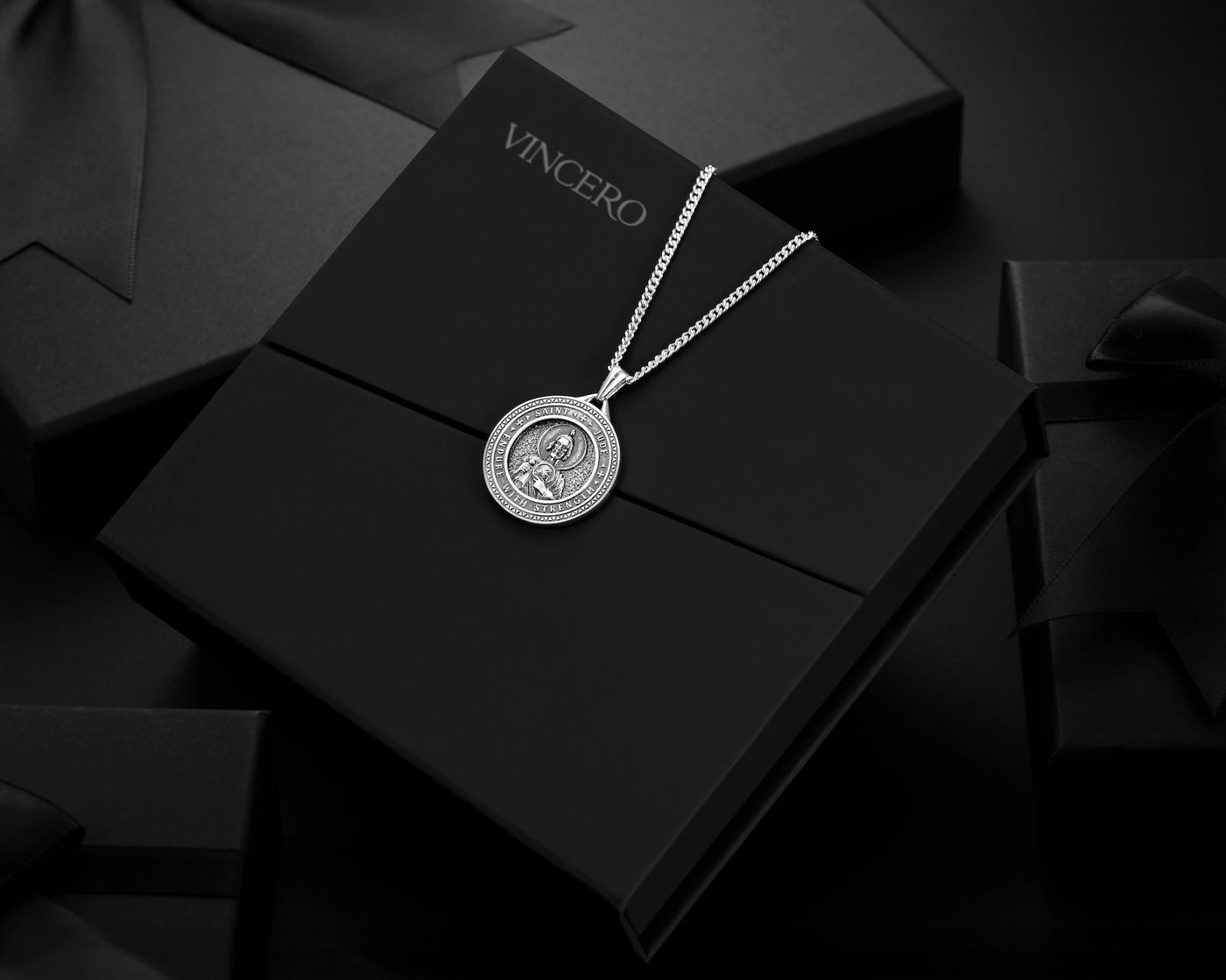 Silver necklace with pendant on a black box with 'Vincero' branding