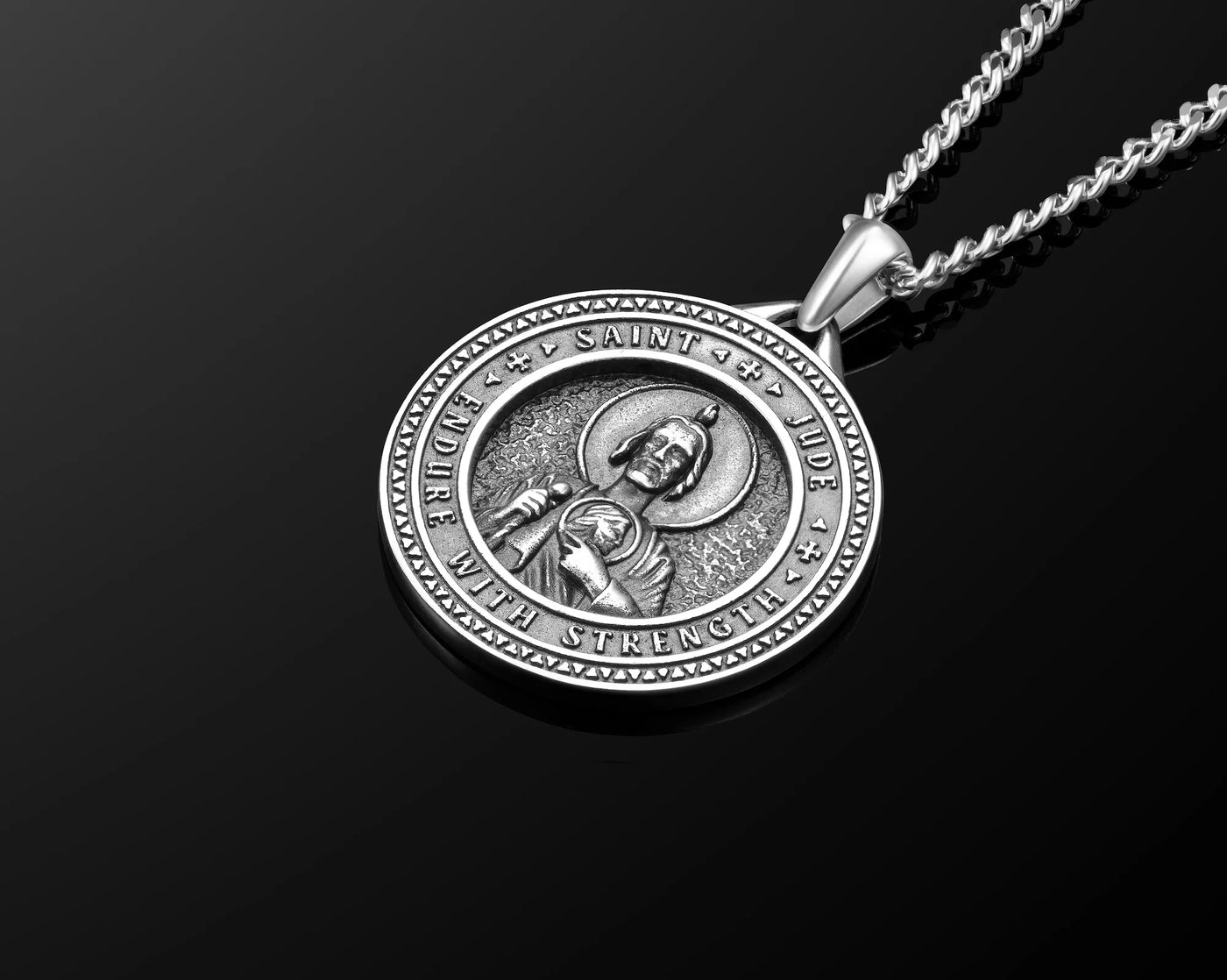 Silver pendant necklace with religious design on a black background