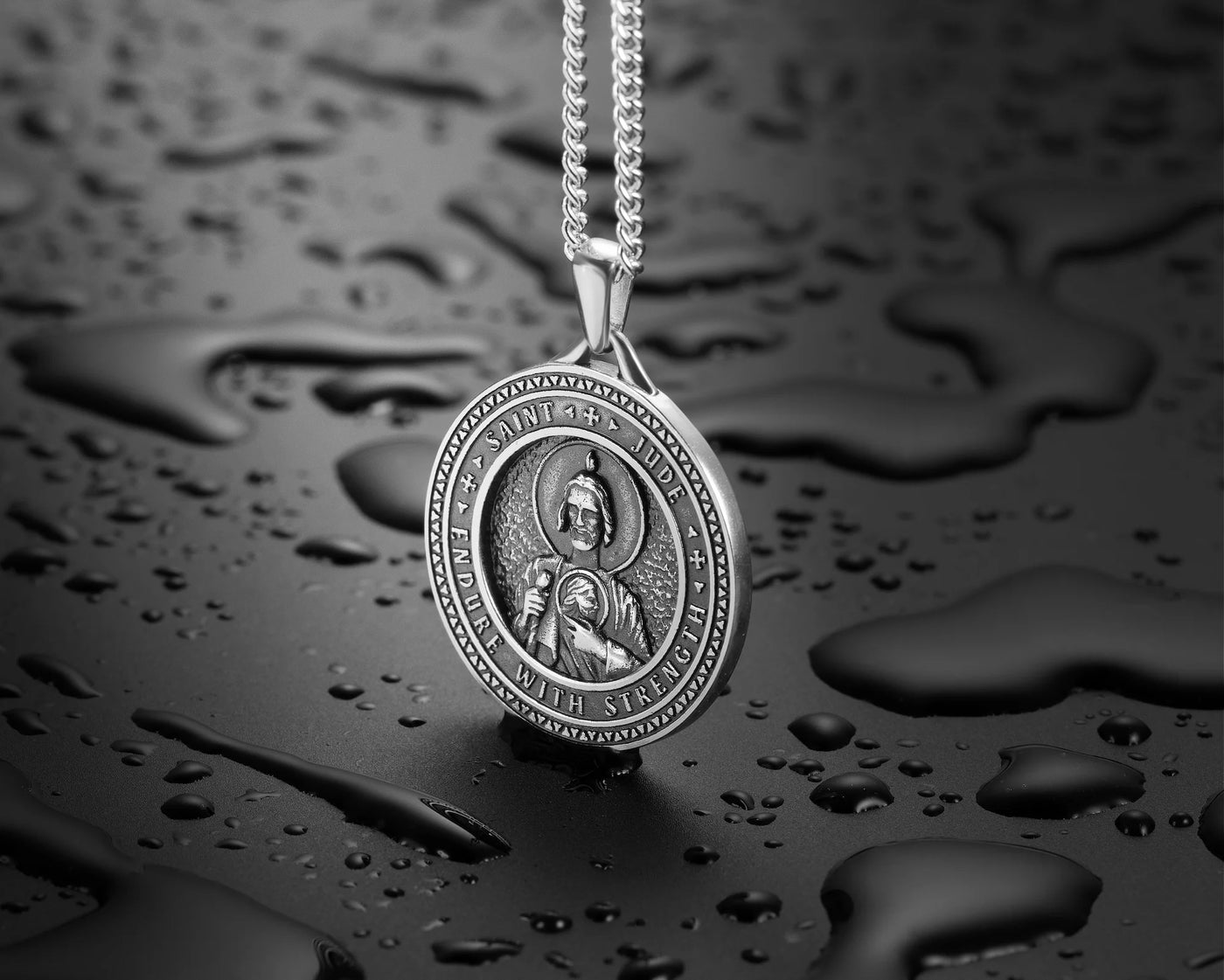 Silver pendant necklace on a dark, water-droplet textured background