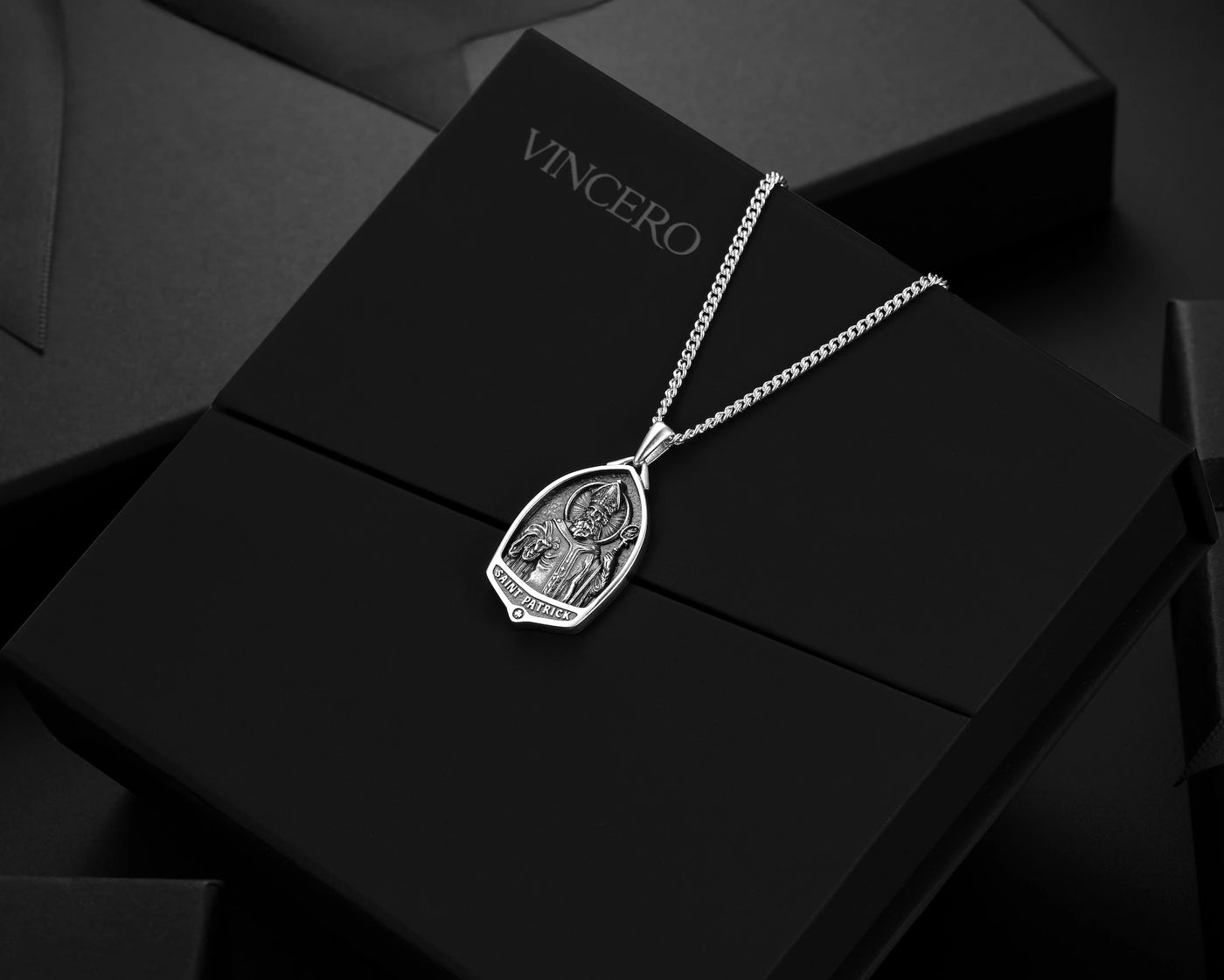 Silver necklace with pendant on a black box branded 'Vincero'.