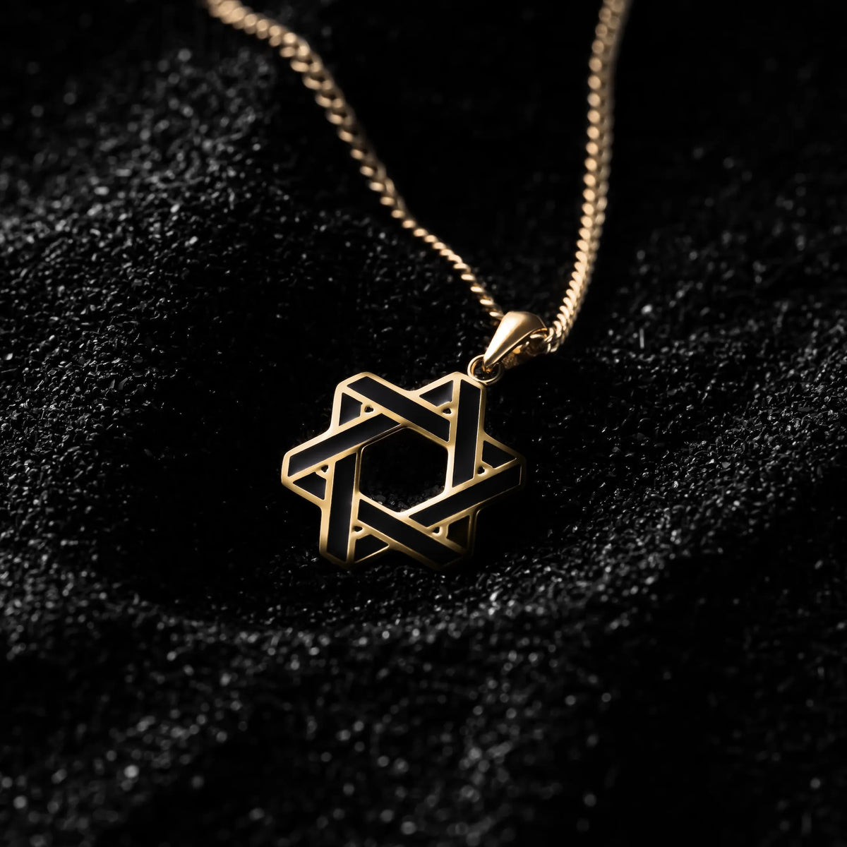 A gold-colored Star of David pendant on a black background, attached to a matching gold-colored necklace.