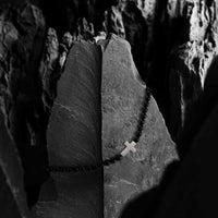 Rosary beads with a cross on a stone surface