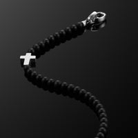 Black beaded bracelet with a silver clasp on a black background