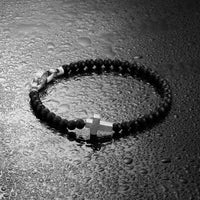 Black rosary with a cross on a wet surface