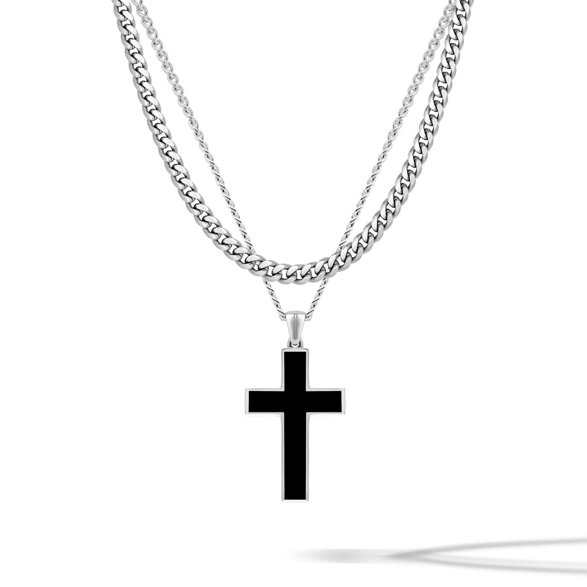 Black cross pendant on a silver chain against a white background