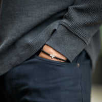 Pocket shot with bracelets cross on wrist
