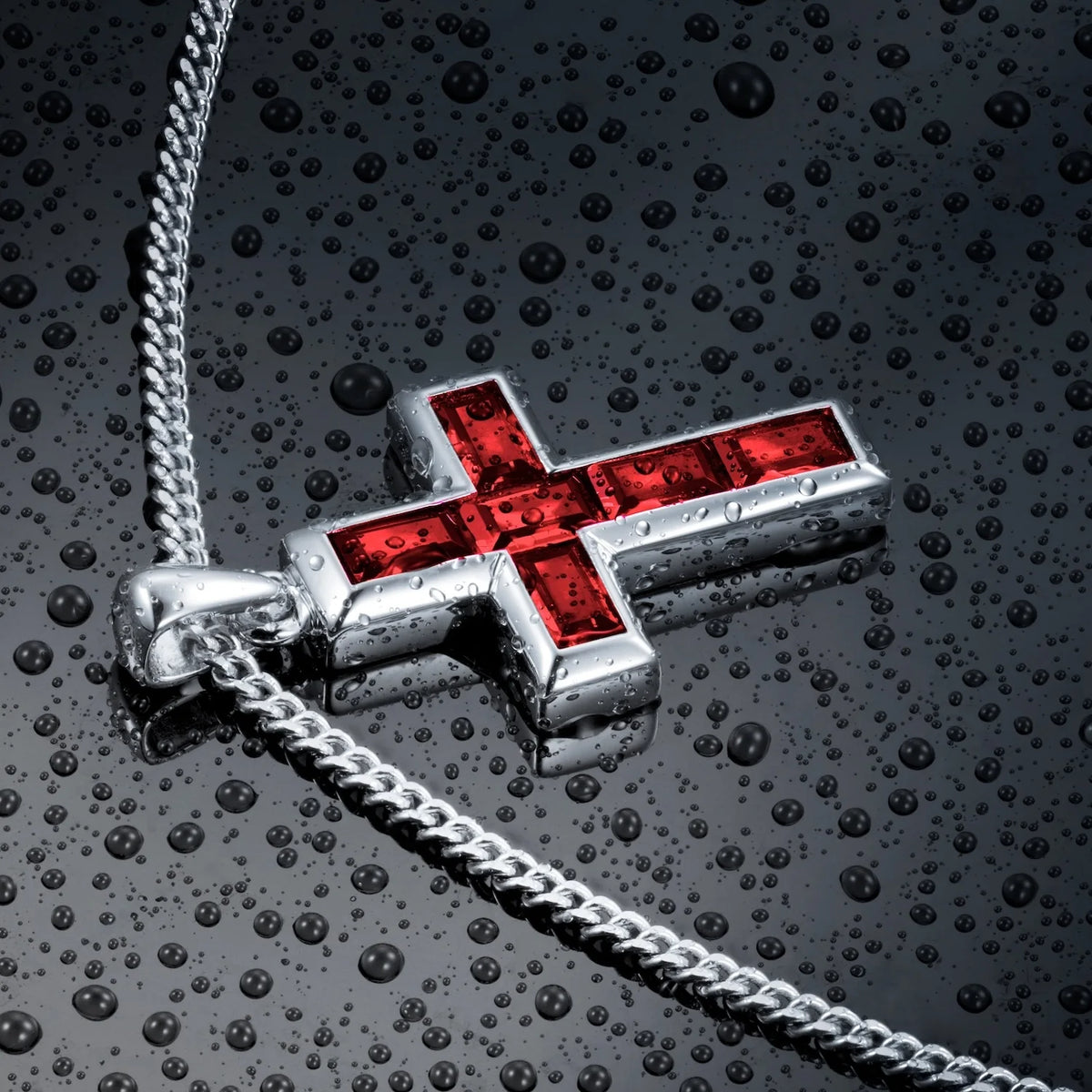 Silver cross pendant with red stones on a chain against a dark textured background