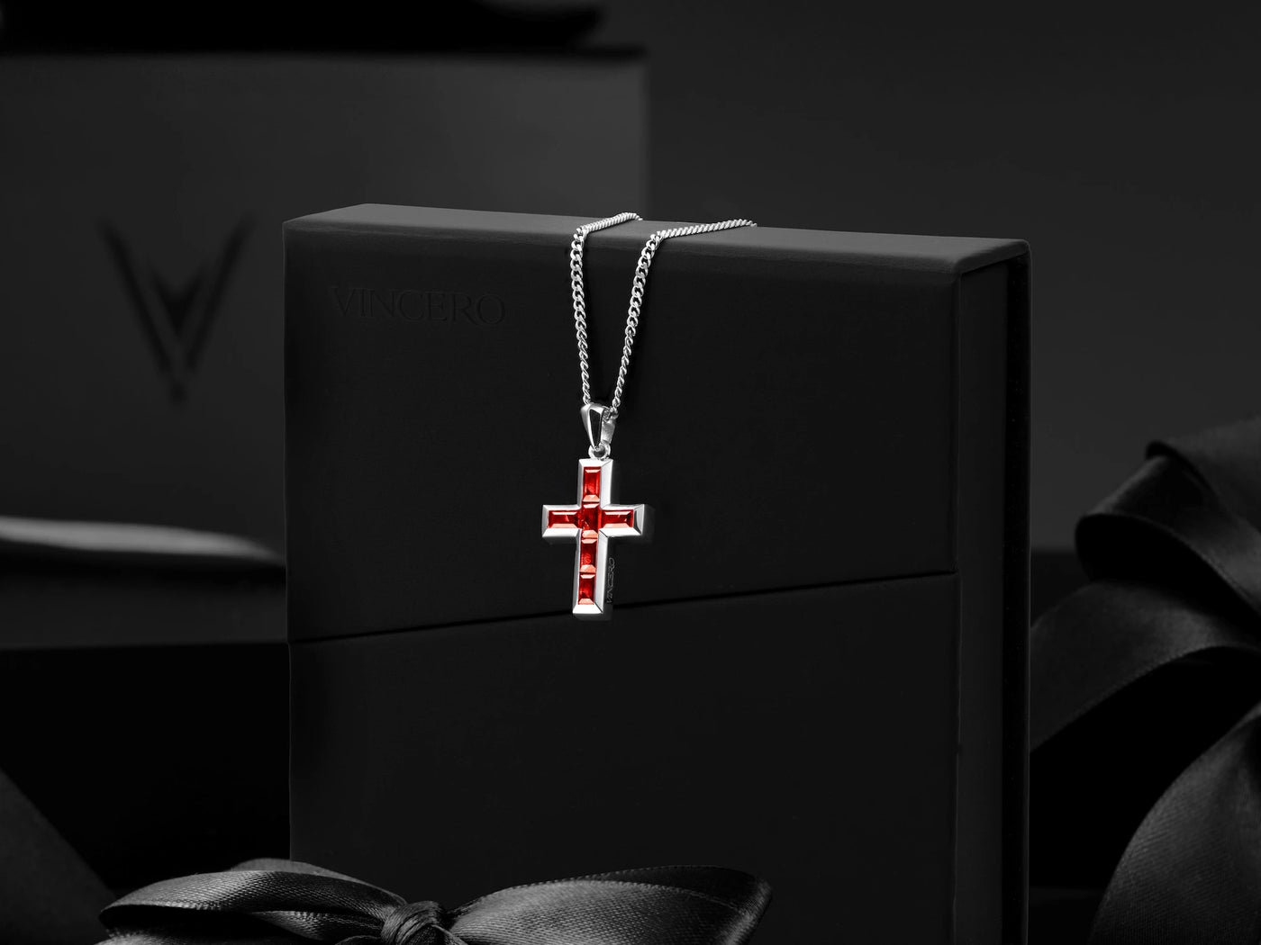 Silver cross pendant with red accents on a black box