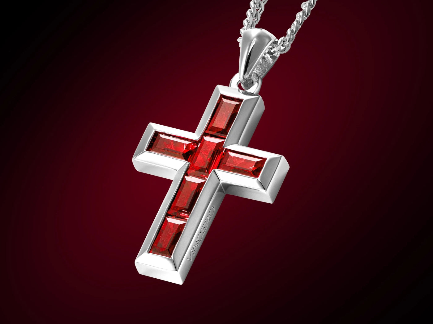 Silver cross pendant with red stones on a dark red background