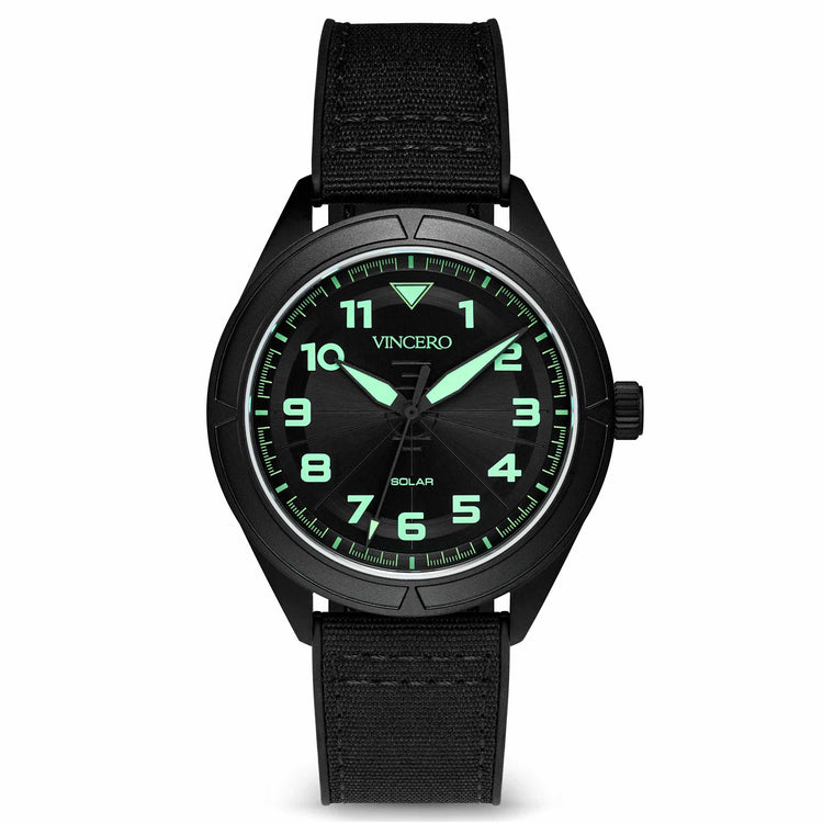 A black analog watch with a silicone band and a stainless steel case, featuring luminous hands and green indices on the dial.