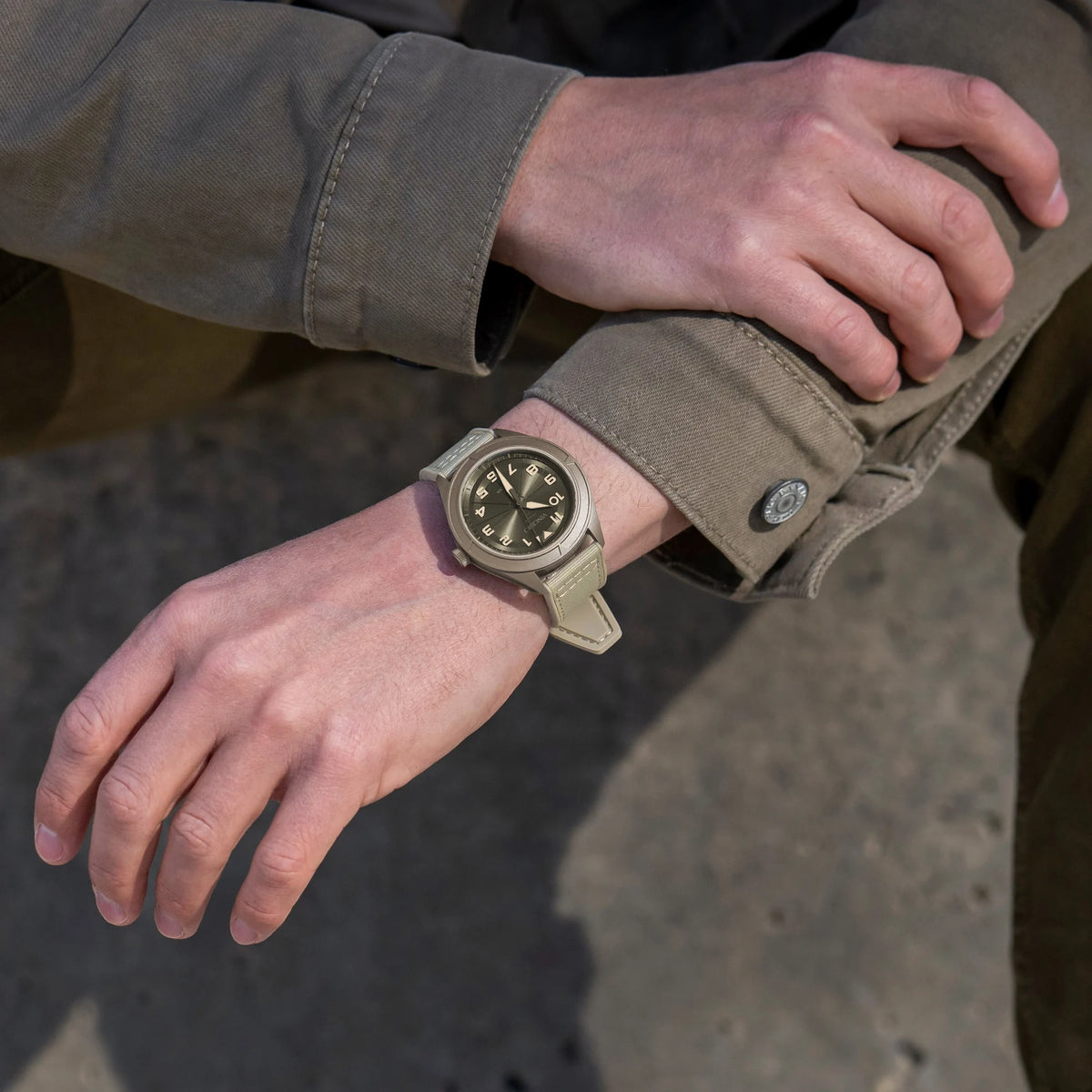 Person wearing a watch with a brown strap on a blurred background