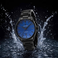 Black wristwatch with blue dial emerging from water on a dark background