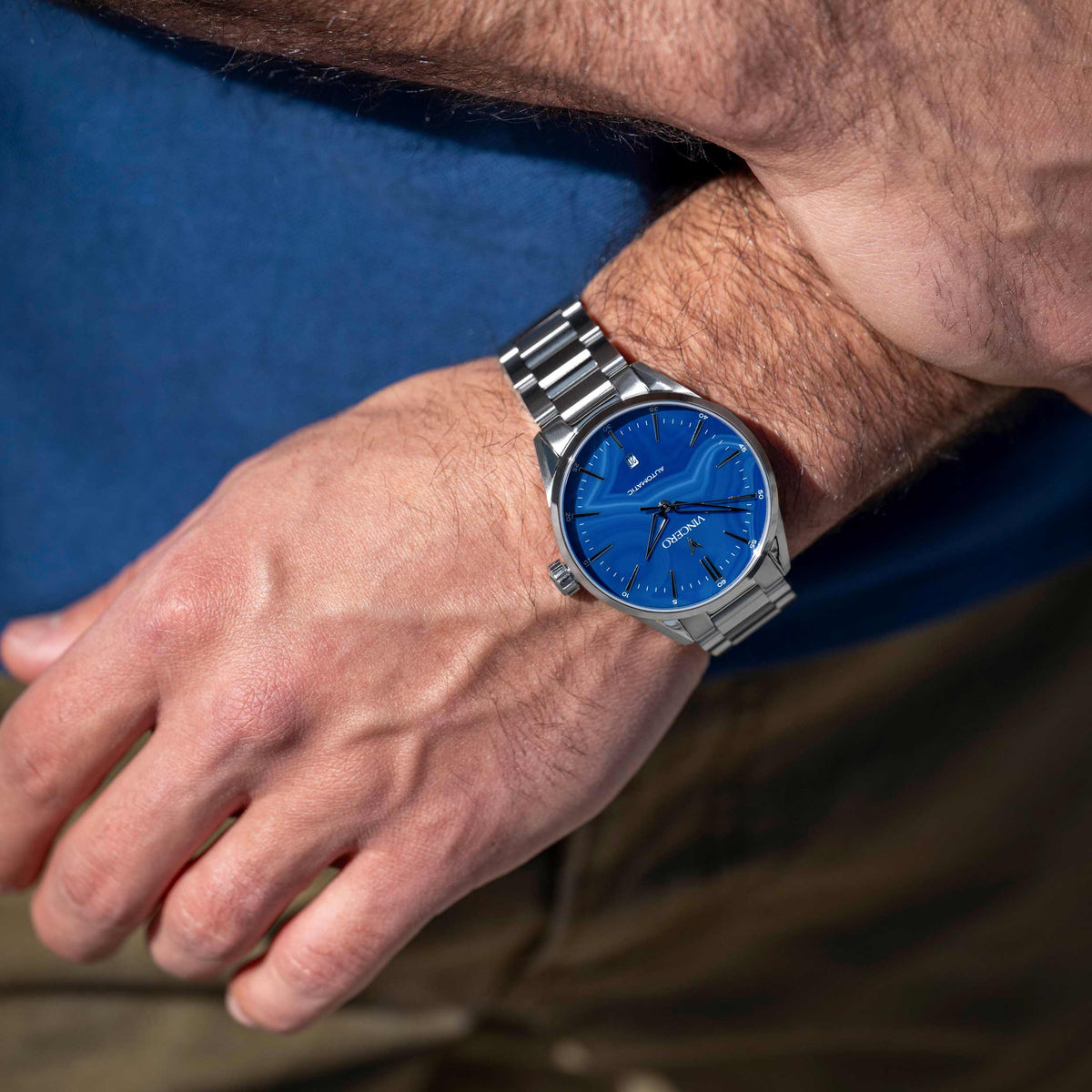 Close-up of a wrist wearing a watch with a blue face and silver band.