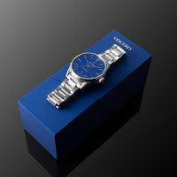 Silver watch with blue face on a blue Vincero box against a dark background
