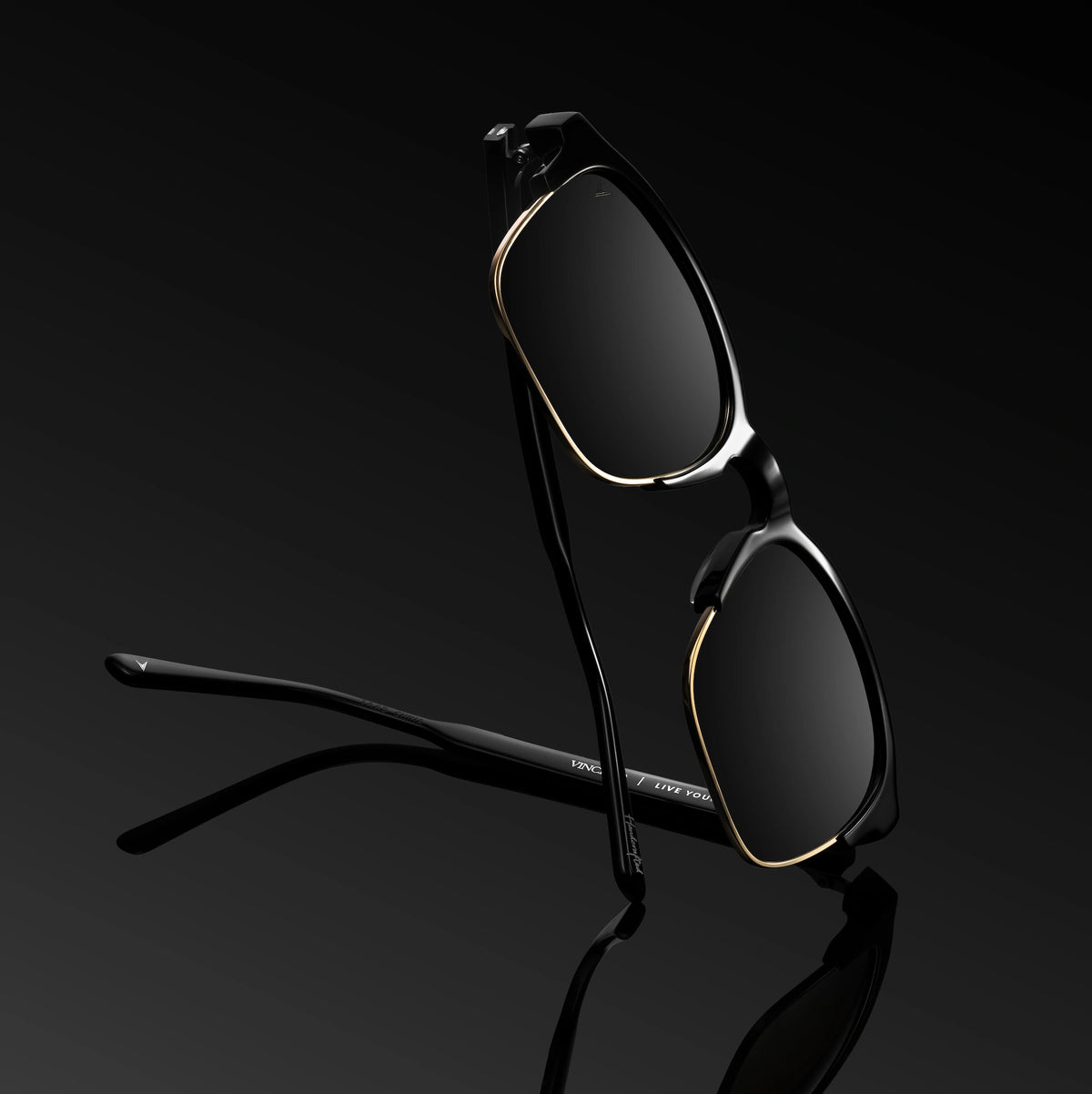 Black sunglasses with gold accents on a black background