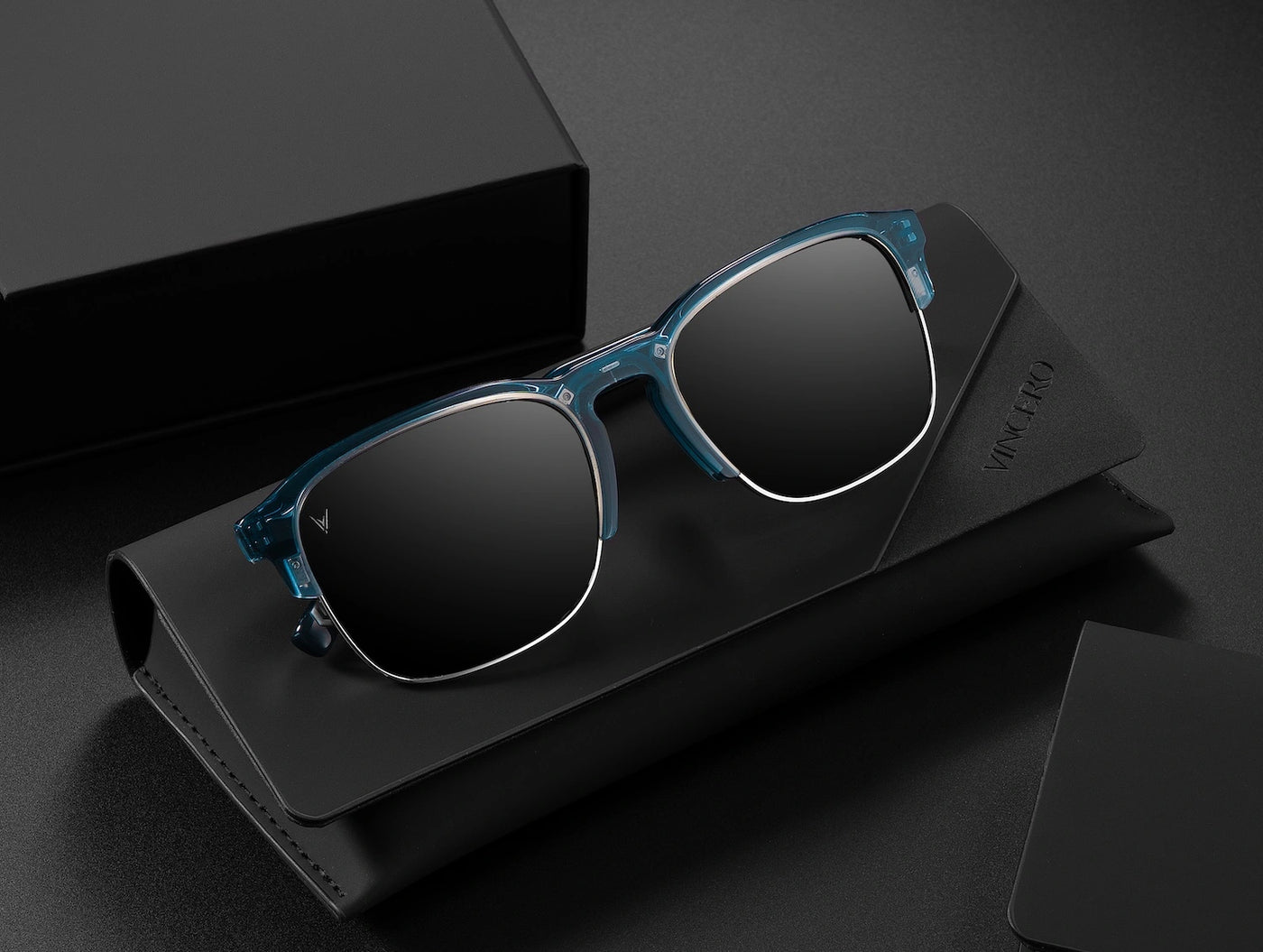Blue sunglasses with dark lenses on a black case against a dark background