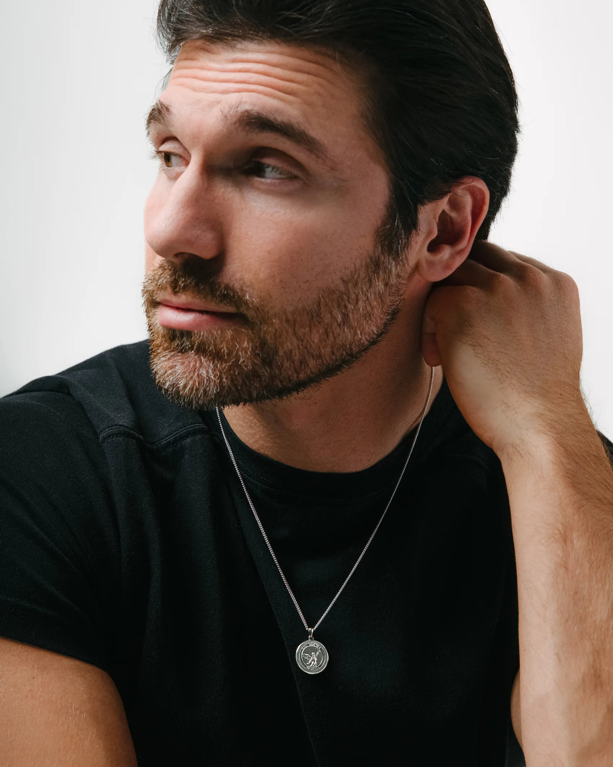 A sterling silver necklace with a round pendant featuring an embossed design, displayed against a white background.