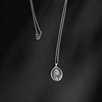 Silver necklace with a pendant on a black background
