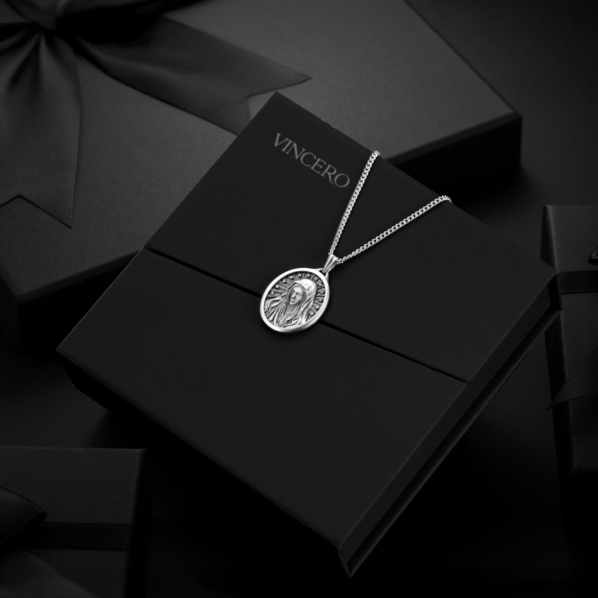 Silver necklace with pendant on a black box with 'Vincero' branding