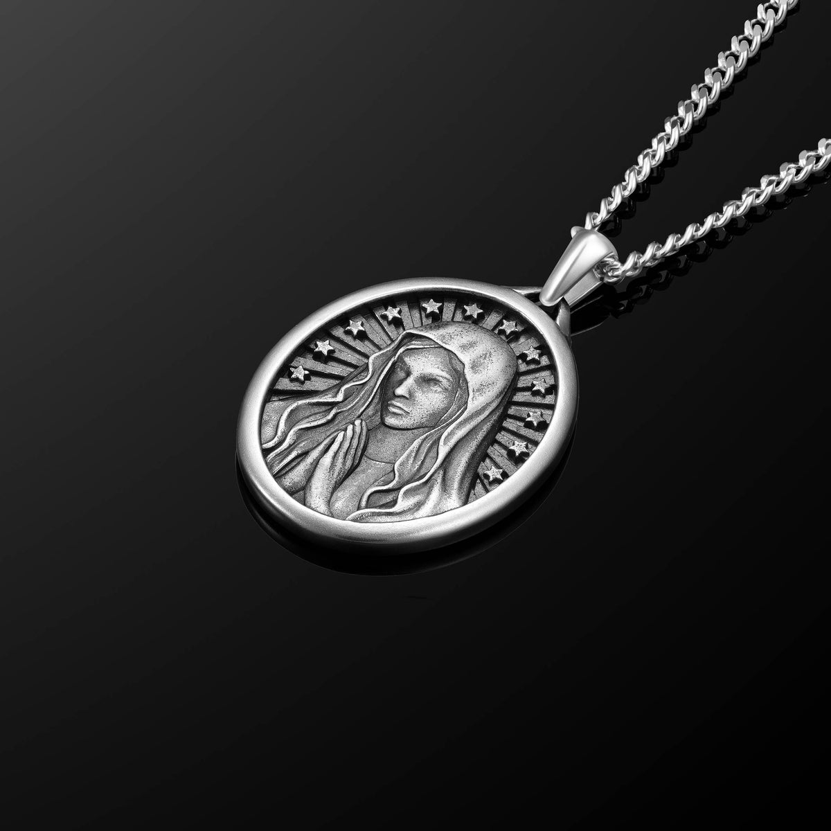 Silver pendant necklace with a detailed design on a black background
